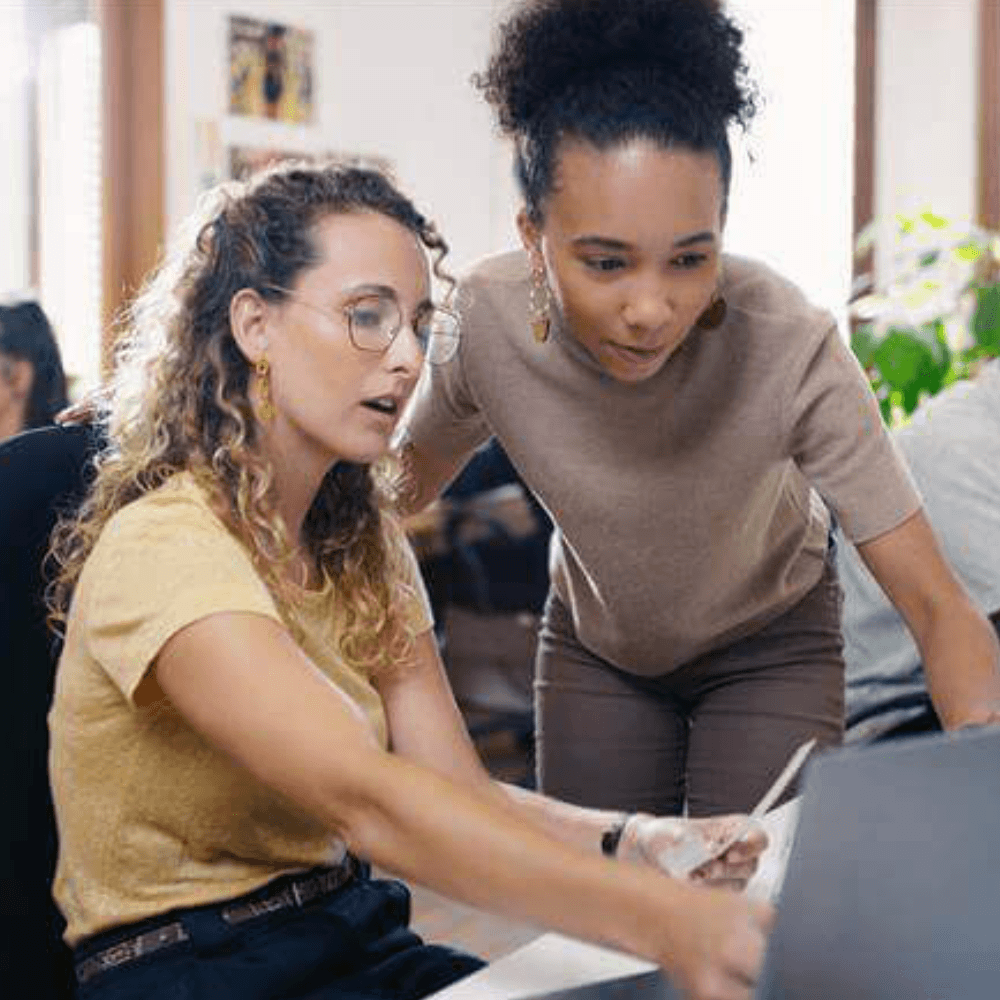 Two female colleagues looking at computer screen together