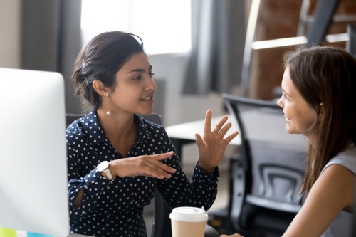 women talking to another women whilst drinking coffee 